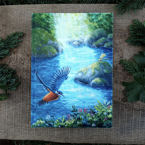 Carnet peint à la main sans les tons bleus avec une rivière et un martin-pêcheur en vol.