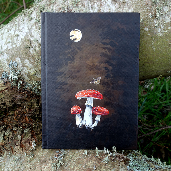 Carnet peint à la main, marron foncé avec la lune, des champignons et un papillon.